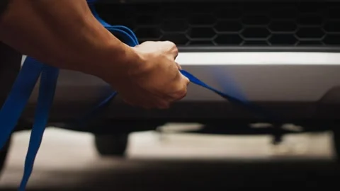 Hands Tying Blue Strap on Front of Car Stock Footage 344235812