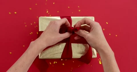 Hands tying a bow on a gift red background Stock Footage 181889034