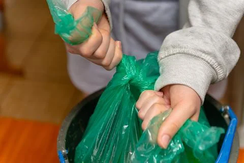 Hands tying a knot on a green garbage bag Stock Photos