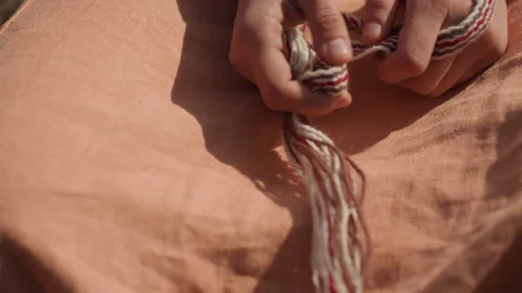 Hands tying a knot on sandy outdoor terrain with concentrated precision and care Stock Footage 343685940