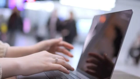 Hands type on a laptop while people move in the background Stock Footage 341452127