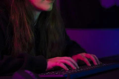 Hands typing on a backlit keyboard in pink and purple neon light Stock Photos