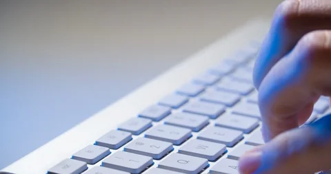 Hands typing on computer bluetooth keyboard with some blue light of office work 库存影片 87459612