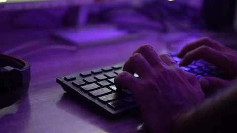 Hands Typing on a Computer Keyboard Under Creative Purple Ambient Lighting Stock Footage 345363601