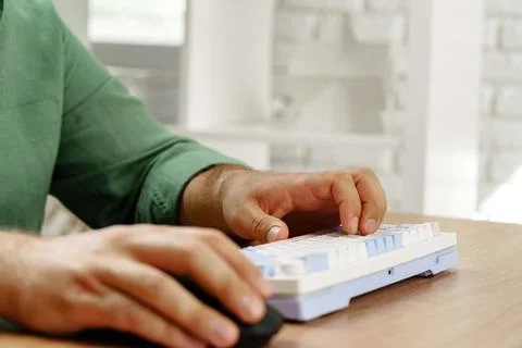 Hands typing on a computer keyboard while using a mouse in a modern workspace 写真素材