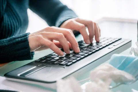 Hands typing computer while teleworking with mask and handkerchiefs on table Stock Photos