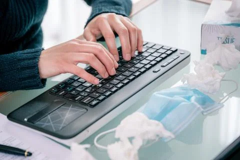 Hands typing computer while teleworking with mask and handkerchiefs on table Stock Photos