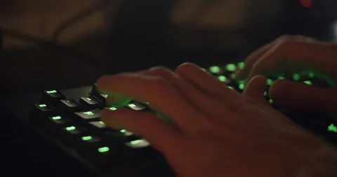 Hands Typing on Gaming Keyboard Glowing Green in Dark Room Stock Footage 115579736
