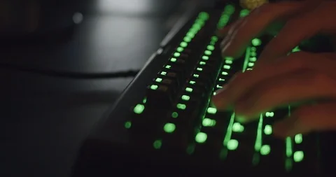 Hands Typing on Gaming Keyboard Glowing Green in Dark Room Stock Footage 115580759