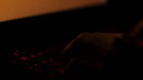 Hands typing on glowing keyboard in the dark lit by changing laptop screen light Stock Footage 79510682