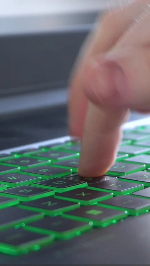 Hands typing on green backlit laptop keyboard in close up view Stock Footage 335829466
