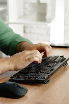 Hands typing on a keyboard beside a computer mouse during a work session at home 스톡 사진