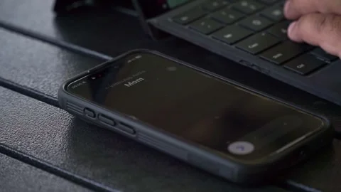 Hands typing on keyboard beside smartphone with incoming call notification. Stock Footage 341458479