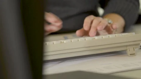 Hands Typing on Keyboard at Desk in Office Close Up with Papers and Documents Stock Footage 334542609