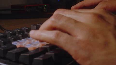 Hands typing on keyboard from sharp angle in warm light Vídeo Stock 327353006
