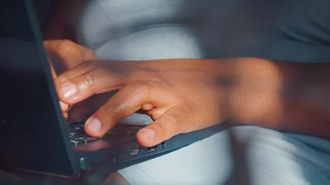 Hands typing on a laptop computer keyboard while working from bed 스톡 동영상 346685503