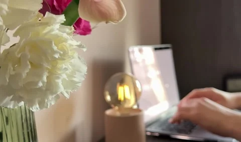 Hands typing on laptop with flowers in background Stock Footage 307162153
