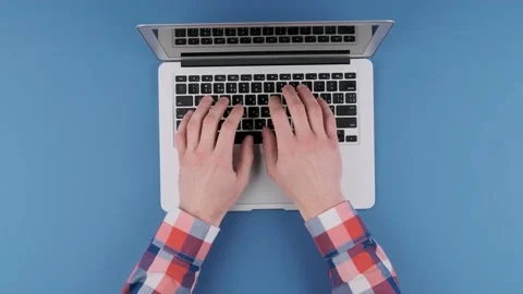 Hands typing on laptop keyboard on blue background. Top view. Stock Footage 141017380
