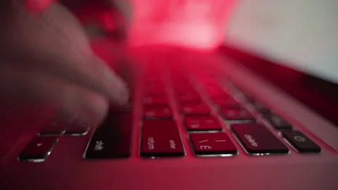 Hands typing on a laptop keyboard in the dark with red lighting Stock Footage 171851282