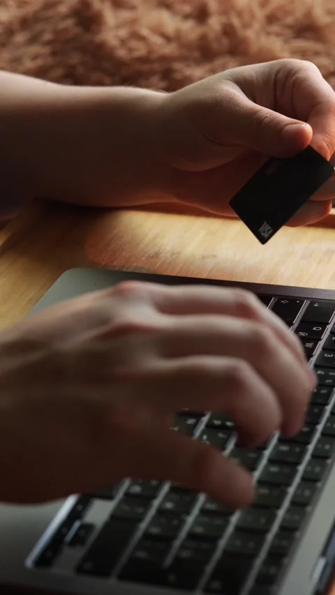 Hands typing on laptop keyboard while holding a credit card for online shopping Stock-Footage 343838133