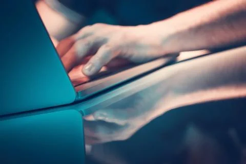 Hands Typing on a Laptop With Reflection on a Glossy Surface in a Dimly Lit.. Stock Photos