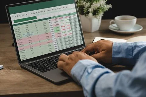 Hands typing on laptop with spreadsheet data and financial graphs on screen.. Stock Photos