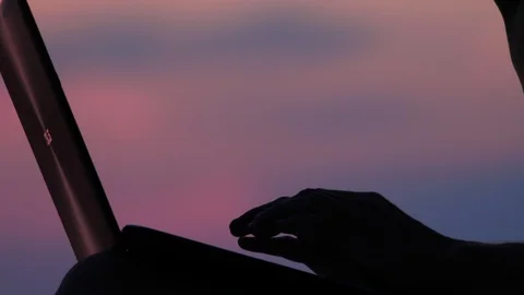 Hands typing on laptop with sunset on background. Internet connection. Quality Stock Footage 114261335