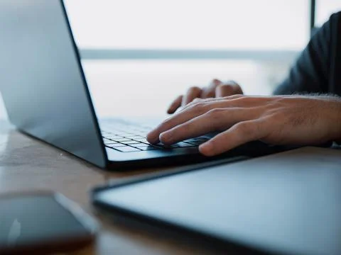 Hands typing on a laptop at a work table Stock-Fotos