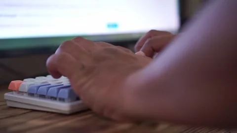Hands typing on mechanical keyboard, blurred computer screen background, work Stock Footage 342634713