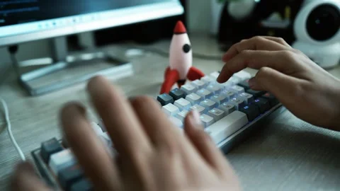 Hands Typing on a Mechanical Keyboard with Rocket Figurine, A close-up of h.. Stock Footage 304910386