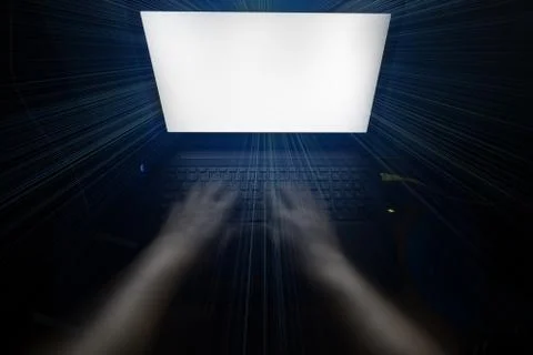 Hands typing on a notebook keyboard in a dark room. Stock Photos