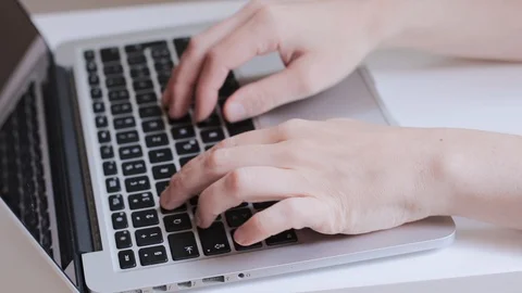 Hands typing quickly on a laptop keyboard in a clear home office space Stock Footage 121889935