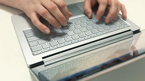 Hands typing quickly on a light gray laptop keyboard in the morning for work or Stock-Footage 316456316