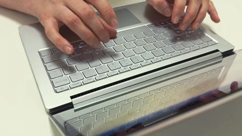 Hands typing quickly on a light gray laptop keyboard in the morning for work or Video stock 317101513