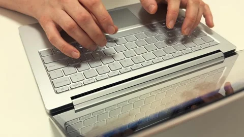 Hands typing quickly on a light gray laptop keyboard in the morning for work or 스톡 동영상 317101844