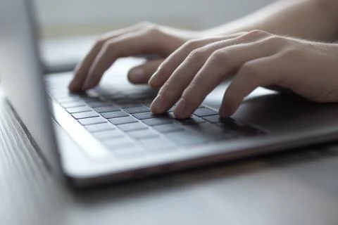 Hands typing on silver laptop computer keyboard, close up Stock Photos