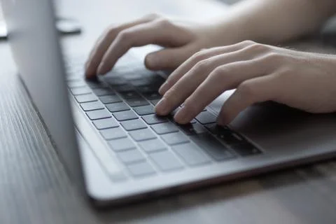 Hands typing on silver laptop computer keyboard, close up Stock Photos