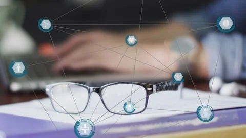 Hands typing starting teal network overlay around glasses on book, showing tech Stock Footage 335235475