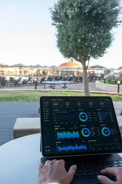 Hands Typing on Tablet with Financial Dashboard at Resort Outdoor Terrace Fotos Stock