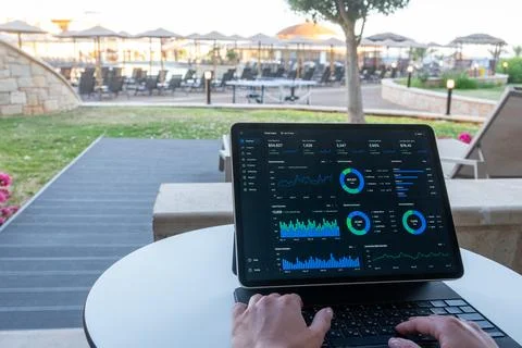 Hands Typing on Tablet with Financial Dashboard at Resort Outdoor Terrace 스톡 사진