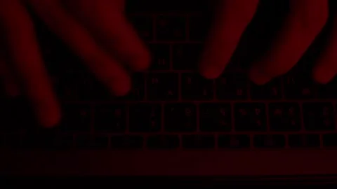 Hands typing text on a keyboard under an alarming red light high angle Stock Footage 229706301