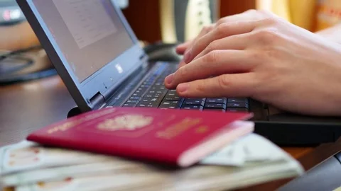Hands typing text on laptop, close-up of money and passports Видео 74502177