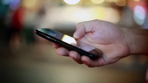 Hands typing text on your mobile phone with bokeh by the road. 1920x1080 Stock Footage 84817314
