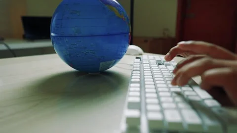 Hands typing on a white keyboard with a globe on the desk Video stock 320725758