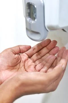 Hands under an automatic wall mounted sanitizer dispenser. Foto stock