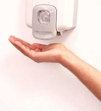 Hands under an automatic wall mounted sanitizer dispenser. Foto stock
