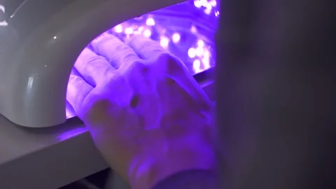 Hands under UV nail lamp during the gel manicure curing process Stock Footage 298300771