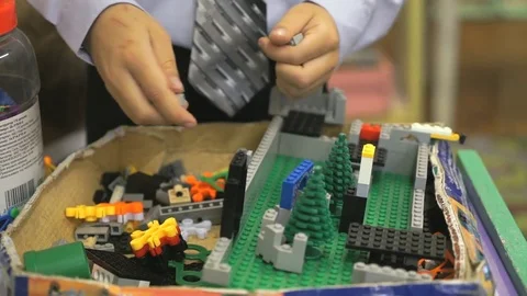 Hands of an unknown boy playing with building kit Видео 80011291