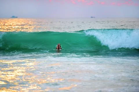 The hands of an unknown lonely floating in the beautiful ocean waves at sunset. Foto stock