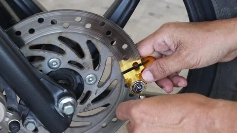 Hands unlock the key of disc brake lock at front wheel on motorcycle Video stock 145716222